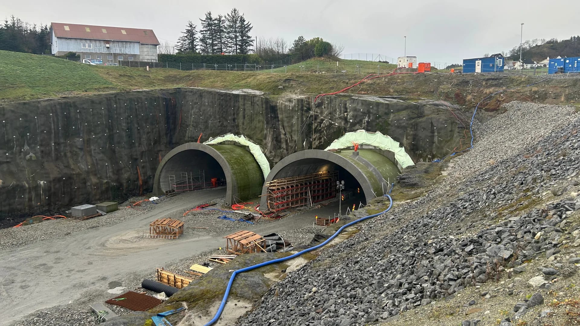 De to tunnelportalene støpt og under tildekking i fjellskjæringen.