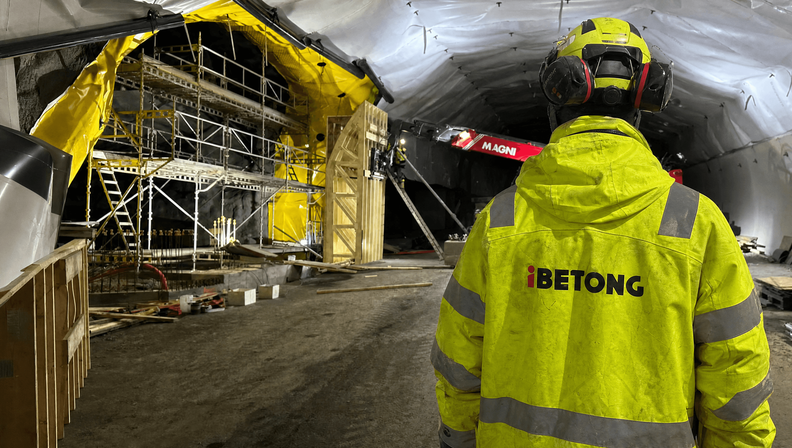 Illustrasjonsbilde av en betongarbeider med Ibetong-jakke foran forskaling og stillas i en tunnel